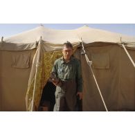 Portrait d'un second-maître de l'équipe de l'ECPA (Etablissement cinématographique et photographique des Armées) en tenue S-3P (survêtement de protection à port permanent), sortant d'une tente saoudienne, et portant un masque à gaz.