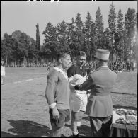Un officier remet une coupe à un joueur de rugby lors d'une compétition.