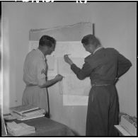 Deux légionnaires à leur bureau travaillant sur une carte.