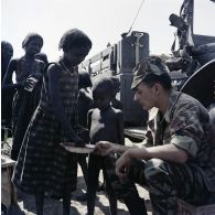 Un soldat français partage son repas avec des enfants tchadiens pendant une halte.