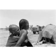 Une femme qui porte un enfant sur son dos dans un village nomade du Tchad.