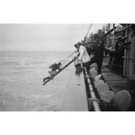 Depuis un dragueur de mines (Minensuchboot), un marin allemand récupère une bouée de sauvetage tombée à la mer.
