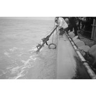 Depuis un dragueur de mines (Minensuchboot), un marin allemand récupère une bouée de sauvetage tombée à la mer.