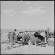 Sahara. Des soldats examinent une voiture abandonnée.