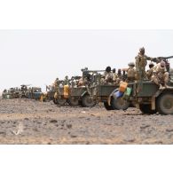 Des soldats maliens sécurisent la progression d'un convoi à bord de leurs pick-ups au bord d'une piste de la région de Gao, au Mali.