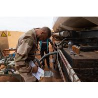 Le brigadier-chef Jean-Maurice, technicien des tests de carburant, contrôle la conteneur d'eau dans l'essence d'un camion-citerne sur la base de Gao, au Mali.