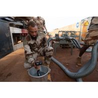 Le brigadier-chef Jean-Maurice, technicien des tests de carburant, contrôle la condensation de l'essence d'un camion-citerne sur la base de Gao, au Mali.