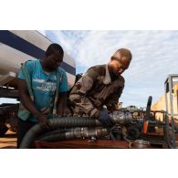 Le brigadier-chef Jean-Maurice, technicien des tests de carburant, branche le tuyau d'un camion-citerne pour remplir un bac souple sur la base de Gao, au Mali.
