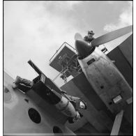 Avant un départ en mission, un mécanicien et un armurier assurent la vérification d'un moteur et arriment une charge sur un hydravion d'exploration Latécoère sur la base d'aéronautique navale de Lanvéoc-Poulmic.