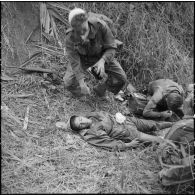 Le médecin-lieutenant Patrice Le Nepvou de Carfort du 8e bataillon de parachutistes de choc (BPC) apporte les premiers secours à un parachutiste autochtone blessé aux jambes au cours d'une reconnaissance au nord de Diên Biên Phu.