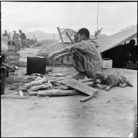 Parachutiste autochtone préparant le feu pour la popote sur sur le camp fortifié de Diên Biên Phu.