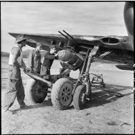 Installation d'une bombe sous l'aile d'un avion Curtiss SB2C Helldiver sur le terrain d'aviation de Diên Biên Phu.