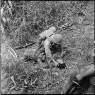Un parachutiste du 8e bataillon de parachutistes de choc (BPC) blessé aux jambes est secouru par un de ses camarades au cours d'une reconnaissance au nord de Diên Biên Phu