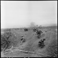 Fantassins progressant sous les tirs au cours d'une offensive menée avec l'appui de blindés contre des positions de l'Armée populaire vietnamienne à Diên Biên Phu.