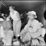 Mme Pidot, assistante sociale, distribue du lait aux soldats de l'Union française libérés à Viet Tri à bord d'un bâtiment de débarquement qui les rapatrie vers Hanoï.