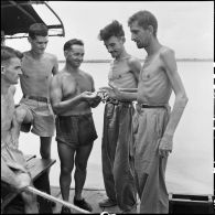Des soldats de l'Union française libérés par l'Armée populaire vietnamienne partagent une cigarette à bord du bâtiment de débarquement qui les rapatrie vers Hanoï.
