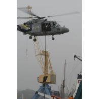 Vol stationnaire d'un hélicoptère Lynx au-dessus de l'Alcyon dans le port de Brest et descente d'un commando marine à la corde lisse.