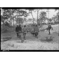 Brancardiers transportant un blessé sur des troncs d'arbre dans le bois de Trou-Bricot. [légende d'origine]