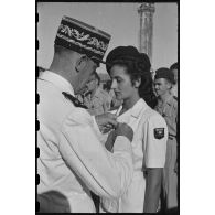Le général de division Leblanc, commandant les Forces terrestres du Centre-Vietnam (FTVC), remet la croix de guerre à Mademoiselle Christiane Sacquet, infirmière.