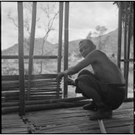Un villageois de Muong Khoua reconstruit sa paillote endommagée par les troupes du vietminh.