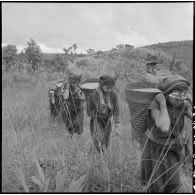 Des chasseurs laotiens de la colonne du chef de bataillon Vaudrey croisent des femmes portant des paniers de paddy.
