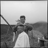 Séance de coiffure pour un chasseur du 5e bataillon de chasseurs laotiens sur un point d'appui à Muong Khoua.