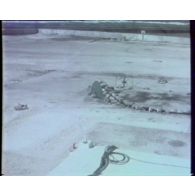 Plan fixe depuis la caméra d'une installation militaire du poste de commande de tir (PCT), sur une plateforme à Moruroa (Mururoa) au cours d'un tir nucléaire sous-marin Codros et extraits de liaisons radio avec un hélicoptère en survol la zone de tir.