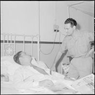 Le cameraman André Lebon, blessé à Diên Biên Phu, s'entretient avec le photographe Pierre Ferrari pendant sa sonvalescence à l'hôpital Grall de Saigon.