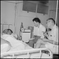 Le journaliste Jacques Chancel (Radio France-Asie) et John Roderick (Associated Press) au chevet d'un sergent du 8e bataillon de parachutistes coloniaux blessé à Diên Biên Phu et rapatrié à l'hôpital Grall de Saigon.