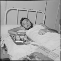 Un sergent-chef du 2e bataillon thaï blessé à Diên Biên Phu et rapatrié à l'hôpital Grall de Saigon se repose dans un lit.
