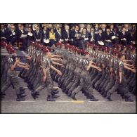 Défilé à pied lors de la cérémonie du 14 juillet 1977 place Joffre devant l'Ecole militaire. Passage d'une unité parachutiste, peut-être le 9e régiment de chasseurs parachutistes (9e RCP), devant la tribune d'autorités civiles invitées.