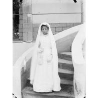 98. [Algérie, 1905-1914. Portrait d'une jeune fille en robe de communiante.]