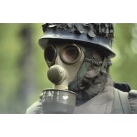 Portrait d'un militaire en tenue NBC (risque nucléaire, bactériologique et chimique) S-3P (survêtement de protection à port permanent) avec ANP (appareil normal de protection) et casque F1 dans un bois.