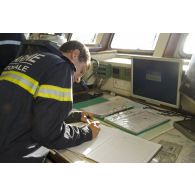 Un officier marinier ajoute une entrée sur le journal de bord en passerelle de La Gracieuse, en Guyane française.