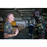 Un officier français discute avec son homologue sénégalais pour un briefing à bord du porte-hélicoptères amphibie (PHA) Tonnerre (L9014) à N'Gazobil, au Sénégal.