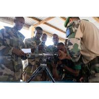 Un instructeur du 2e régiment étranger de parachutistes (REP) présente une mitrailleuse d'appui général (FN MAG) à des élèves sous-officiers ivoiriens à Bouaké, en Côte d'Ivoire.