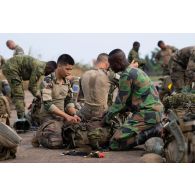 Un légionnaire du 2e régiment étranger de parachutistes (REP) aide un soldat ivoirien à préparer son équipement pour partir en mission sur l'aéroport de Bouaké, en Côte d'Ivoire.