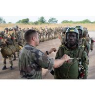 Un légionnaire du 2e régiment étranger de parachutistes (REP) contrôle l'équipement d'un soldat ivoirien pour partir en mission sur l'aéroport de Bouaké, en Côte d'Ivoire.