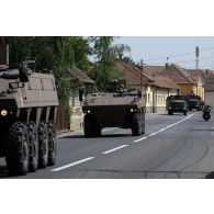 Des véhicules blindés de combat d'infanterie (VBCI) et des camions équipés d'un système d'artillerie (CAESAR) traversent le village de Voila sur la route de Cincu, en Roumanie.