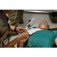 Une infirmière du Service de santé des armées (SSA) prépare une transfusion de plasma lyophilisé pour un blessé ayant subi un choc hémorragique traumatique au Rôle 1 de Cincu, en Roumanie.