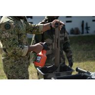 Un soldat portugais décontamine un fusil à pompe Benelli Supernova sous la supervision d'un instructeur du 2e régiment de dragons (RD) à Cincu, en Roumanie.