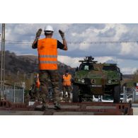 Des soldats guident le chargement d'un véhicule blindé léger (VBL) à bord d'un train en gare de Voila, en Roumanie.