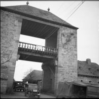 Une porte d'entrée d'une commune du Bade-Wurtemberg. Un convoi de véhicules français et américains passe cette porte.