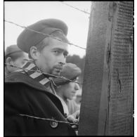 Portrait d'un déporté derrière des barbelés du camp de Vaihingen récemment libéré par des troupes françaises.