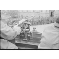 Prisonniers de guerre allemands rassemblés, sous la surveillance du servant d'une mitrailleuse 12,7 mm d'un scout car ou d'un half-track.