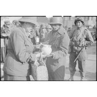 Distribution de vivres par la Croix-Rouge à des soldats français et à des prisonniers de guerre allemands rassemblés dans une commune.