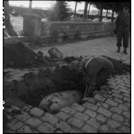 Excavation par un prisonnier allemand d'une bombe non explosée à Lorient.