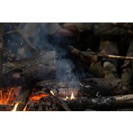 Un soldat du 35e régiment d'infanterie (RI) fait sécher son gant au feu de bois lors d'un bivouac à Lunca de Sus, en Roumanie.
