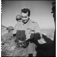 Le caméraman du service cinématographique de l'Armée (SCA) Jacques Natteau charge sa caméra Le Blay.