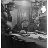 Le commandant du cargo danois Anna saisi, renseigne et signe les documents du bord et ceux remis par un officier de la police de la navigation.